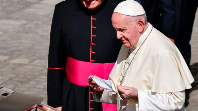 El Papa Francisco sostiene su mascarilla cuando se va al final de una audiencia pública limitada. Foto: AFP.