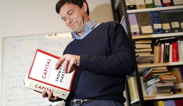 French economist and academic Thomas Piketty, poses in his book-lined office at the French School for Advanced Studies in the Social Sciences (EHESS), in Paris May 12, 2014. The 43-year-old Piketty's book "Capital in the Twenty-First Century" has attracted praise and invective alike on its way to the top of the Amazon.com books best-seller list. Picture taken May 12, 2014.  REUTERS/Charles Platiau (FRANCE - Tags: POLITICS SOCIETY BUSINESS EDUCATION) - RTR3OZ0F