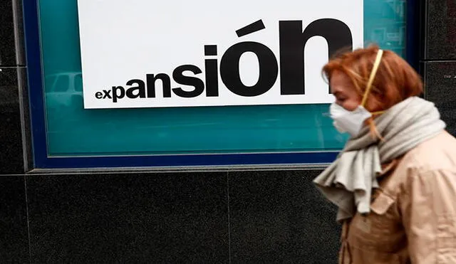 Una mujer con una mascarilla caminaba el lunes junto una sucursal bancaria de Madrid. Foto: EFE