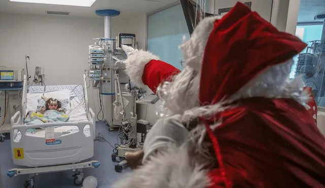 Profesional de la salud vestido de Papá Noel saluda a un niño hospitalizado en Cali, Colombia. Foto: AFP