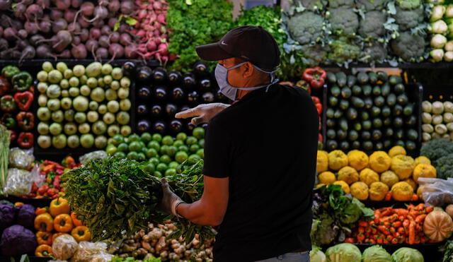 A man wearing a face mask as a preventive measure against the spread of the new coronavirus, COVID-19, buys groceries at a municipal market in Caracas, on March 20, 2020. (Photo by Federico PARRA / AFP)