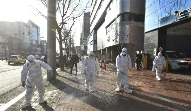 This handout picture taken on February 19, 2020 by Daegu Metropolitan City Namgu shows South Korean health officials wearing protective suit and spraying disinfectant in front of the Daegu branch of the Shincheonji Church of Jesus in the southeastern city of Daegu as about 40 new cases of the COVID-19 coronavirus confirmed after they attended same church services. - A cluster of novel coronavirus infections centred on a cult church in the South Korean city of Daegu leaped to 39 cases February 20, as the country's total spiked for the second successive day. (Photo by Handout / Daegu Metropolitan City Namgu / AFP) / RESTRICTED TO EDITORIAL USE - MANDATORY CREDIT "AFP PHOTO / Daegu Metropolitan City Namgu" - NO MARKETING NO ADVERTISING CAMPAIGNS - DISTRIBUTED AS A SERVICE TO CLIENTS