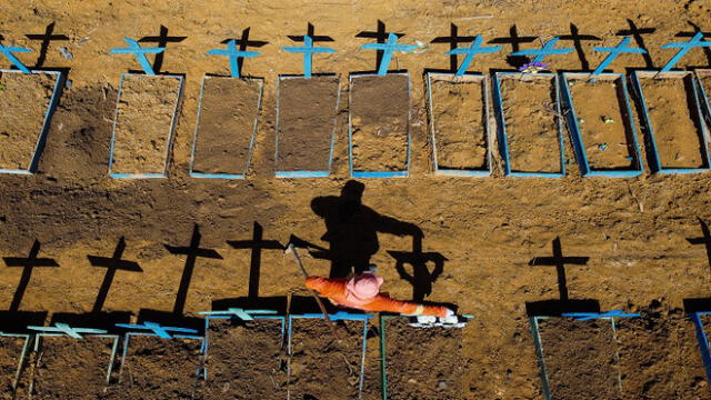 (FILES) This file photograph taken on June 2, 2020, shows an aerial view of a gravedigger standing at the Nossa Senhora Aparecida cemetery where COVID-19 victims are buried daily, in the neighbourhood of Taruma, in Manaus, Brazil, during the novel coronavirus (Covid-19) pandemic. - The coronavirus has upended everyday life in the six months since the crisis was declared a pandemic by the World Health Organization (WHO). While our understanding of the new respiratory disease has steadily increased since it was first detected in China last year, what lies ahead over the next half-year remains unknown. (Photo by Michael DANTAS / AFP)