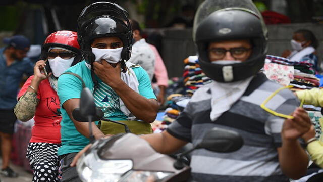 Motorists wearing facemasks as a preventive measure against the spread of the Covid-19 coronavirus, ride through a market in New Delhi on August 30, 2020. - India on August 30 set a coronavirus record when it reported 78,761 new infections in 24 hours -- the world's highest single-day rise -- even as it continued to open up the economy. (Photo by Sajjad  HUSSAIN / AFP)