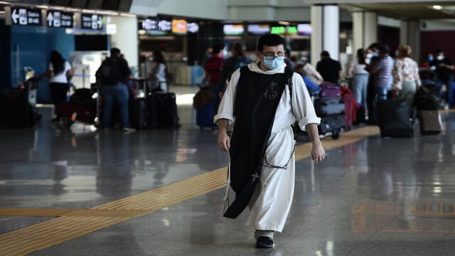 A monk walks across a terminal as people check in at Rome's Fiumicino airport on June 3, 2020, as airports and borders reopen for tourists and residents free to travel across the country, within the COVID-19 infection, caused by the novel coronavirus. (Photo by Filippo MONTEFORTE / AFP)