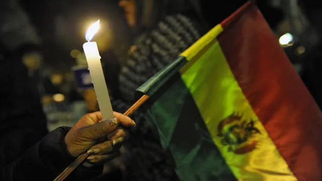 A woman holds a candle and a Bolivian national flag during a vigil in homage of victims of clashes between supporters of defeated presidential candidate Carlos Mesa and supporters of the ruling Movimiento Al Socialismo (MAS) party in La Paz, on November 1, 2019. - President Evo Morales called Thursday for a "truce" while an international body conducts an audit of Bolivia's disputed election results, after clashes between rival groups left two dead and nearly 140 injured. (Photo by JORGE BERNAL / AFP)