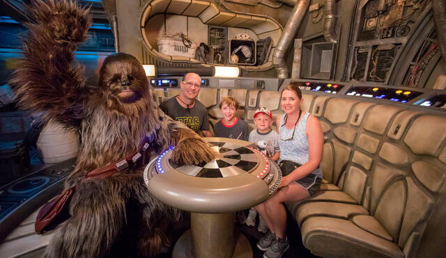 Eight-year-old Jonathan Ridgeway of Ocean Springs, Mississippi (center, back) becomes the one millionth guest to take to take the controls of Millennium Falcon: Smugglers Run at Star Wars: Galaxy’s Edge at Disneyland Resort in Anaheim, Calif., Tuesday, July 16, 2019. Chewbacca joined (l-r) Rodger Ridgeway, Jonathan Ridgeway, 8, Logan Ridgeway, 4, and Becky Ridgeway for a photo. The family was welcomed in the Main Hold of Millennium Falcon with a surprise declaration, which included a visit by Chewbacca, followed by the ride experience and toasting blue and green milk with his family. This significant milestone comes just weeks since the land opened.  (Joshua Sudock/Disneyland Resort)