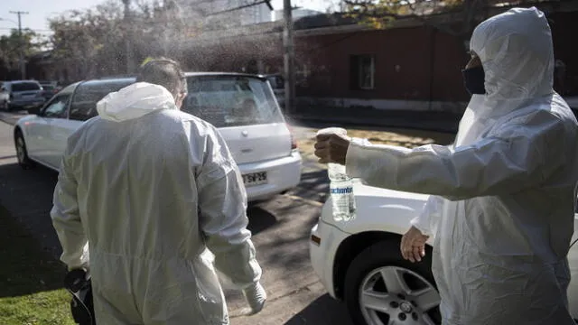 An employee of a funeral home sprays to disinfect a co-worker's protective suit as they wait outside the San Jose public hospital morgue, amid the spread of the coronavirus disease (COVID-19) in Santiago, on June 05, 2020. - Deaths from the coronavirus in Chile have risen by more than 50 percent in the past week, the health ministry announced Friday, despite a three-week lockdown of the capital Santiago. Three months after the country registered its first infection, Health Minister Jaime Manalich reported 4,207 new infections and 92 deaths in the previous 24 hours. (Photo by Martin BERNETTI / AFP)
