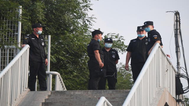 Security personnel stand guard on a pedestrian overpass near the closed Xinfadi market in Beijing on June 13, 2020. - The huge wholesale market has become the centre of focus for a new cluster of coronavirus cases in Beijing, where nervous local officials have begun mass testing, closing schools and neighbourhoods, and turned sharp scrutiny towards the food supply chain. (Photo by GREG BAKER / AFP)