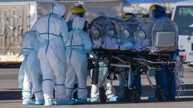 Health workers move a COVID-19 infected patient to a C-130 Hercules, to be taken to the city of Concepcion, at a Chilean Air Force base in Santiago, Chile, on May 24, 2020. - Patients infected with COVID-19 are taken to other cities in the country in order to free up space in the intensive care units of hospitals in Santiago. (Photo by Martin BERNETTI / AFP)