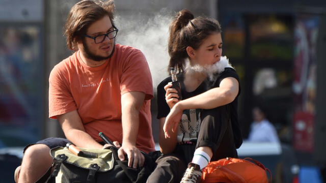 Una pareja fuma cigarrillos electrónicos en el centro de Kiev en un cálido día de otoño el 13 de septiembre de 2019.