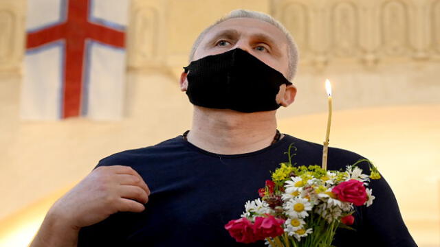 A Georgian Orthodox believer wearing a face mask attends a service celebrating Trinity Sunday in the Holy Trinity Cathedral in Tbilisi on June 7, 2020, as the country eases measures taken to curb the spread of the COVID-19 pandemic, caused by the novel coronavirus. (Photo by Vano SHLAMOV / AFP)