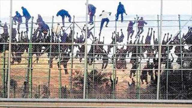 Decenas de migrantes intentan cruzar la valla de Melilla. Al otro lado los espera la Guardia Civil. Foto: Mediterráneo.
