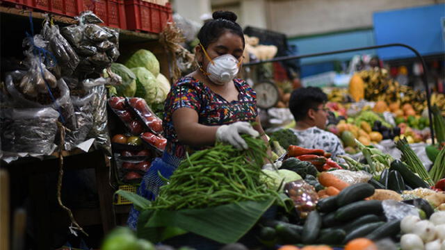 Mujer se protege del coronavirus en mercado de Guatemala. Foto: AFP.