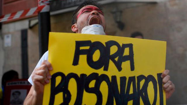 Un ciudadano de Brasil sostiene una pancarta en protesta contra Jair Bolsonaro. Foto: Oscar del Pozo/AFP.