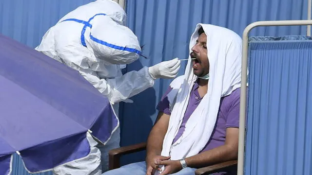 A health official (L) wearing protective gear takes a sample from a man sitting in a temporary cabin at a drive-through screening and testing facility for the COVID-19 coronavirus, alongside a street in Islamabad on June 7, 2020. - Pakistan has confirmed more than 100,000 cases of the coronavirus, health authorities said. (Photo by Aamir QURESHI / AFP)