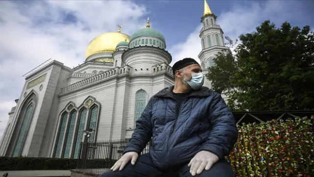 A man wearing a face mask and protective gloves sits in front of the Central Mosque in Moscow on May 30, 2020, amid the COVID-19 outbreak, caused by the novel coronavirus. - Moscow authorities plan to start opening mosques for parishioners starting from June 1, 2020, local media report. (Photo by Alexander NEMENOV / AFP)