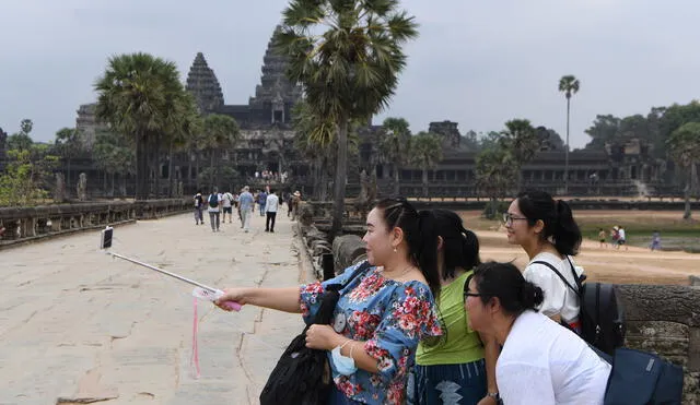 Tourists pose for a selfie during their visit to the Angkor Wat temple in Siem Reap province on March 6, 2020. - The deadly COVID-19 novel coronavirus epidemic will cost world tourism at least $22 billion owing to a drop in spending by Chinese tourists, the head of the World Travel and Tourism Council said on February 27. (Photo by TANG CHHIN Sothy / AFP)