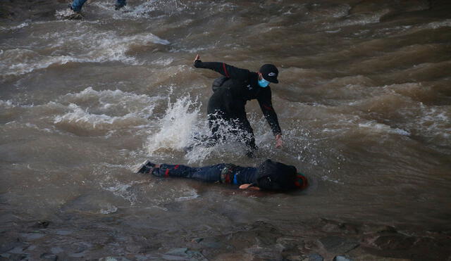 Manifestantes socorren a una persona que se encuentra inconsciente luego de caer en el río Mapocho durante protestas en contra del Gobierno de Sebastián Piñera el viernes. Foto: EFE