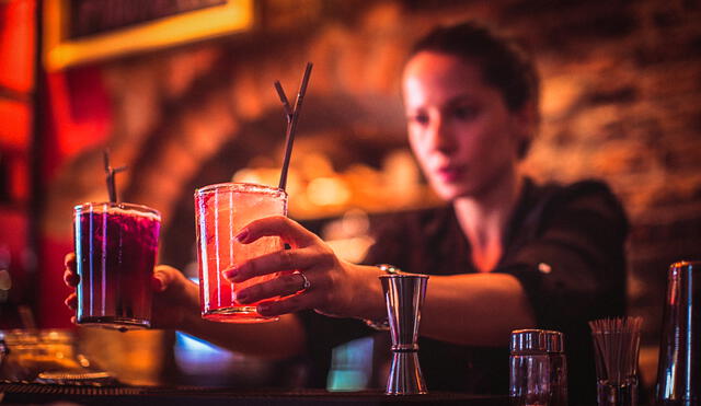 Close-up of a young female bartender serving cocktails in a nightlife cocktail bar. Selective focus. Focus on foreground.