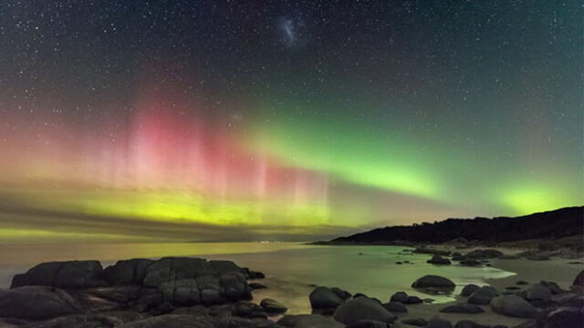Una exhibición de colores brillantes de las Luces del Sur se proyecta hacia el cielo nocturno en la costa este de Tasmania. La Gran Nube de Magallanes también aparece en el centro superior de la imagen. Foto: James Stone