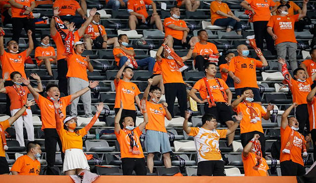 Con el color naranja del equipo y algunos sin mascarilla festejaron el regreso de la hinchada al estadio de Wuhan, donde surgió el coronavirus. Foto: AFP