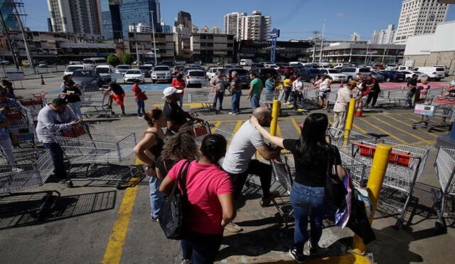 Decenas de personas, algunas con tapabocas, hacen fila este viernes para realizar compras en un supermercado de Panamá. Foto: EFE
