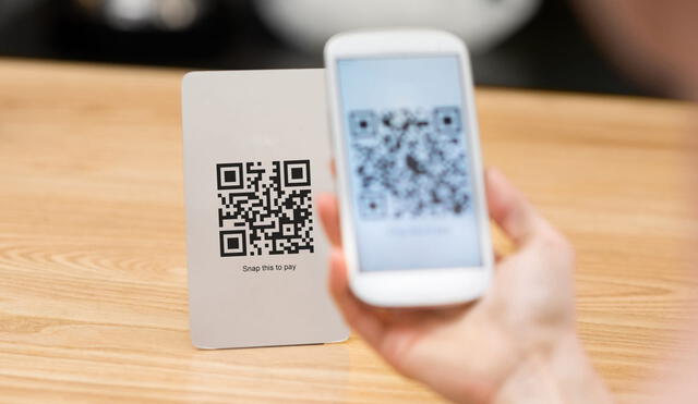Closeup of a hand holding phone and scanning qr code. Woman hand paying with qr code. Close up of customer hand making payment through smart phone and scan code.