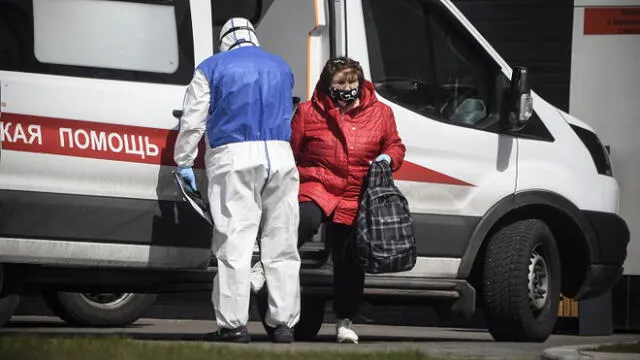 A medic escorts a woman into a hospital where patients infected with the COVID-19 novel coronavirus are being treated in the settlement of Kommunarka outside Moscow on April 28, 2020. (Photo by Alexander NEMENOV / AFP)