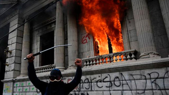 El gesto de un manifestante luego de prender fuego a una oficina del Congreso durante una protesta en Guatemala. Foto: AFP