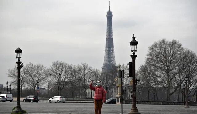 A member of the public wearing a face mask takes a selfie on the empty Place de la Concorde  in Paris, on March on 17, 2020, while a strict lockdown comes into in effect in France to stop the spread of COVID-19, caused by the novel coronavirus. - A strict lockdown requiring most people in France to remain at home came into effect at midday on March 17, 2020, prohibiting all but essential outings in a bid to curb the coronavirus spread. The government has said tens of thousands of police will be patrolling streets and issuing fines of 38 to 135 euros (42-150 USD) for people without a written declaration justifying their reasons for being out. (Photo by Lionel BONAVENTURE / AFP)
