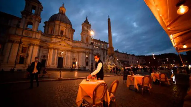 Un empleado limpia una mesa en una terraza vacía en la plaza Piazza Navona en Roma el 23 de octubre de 2020. Foto: AFP