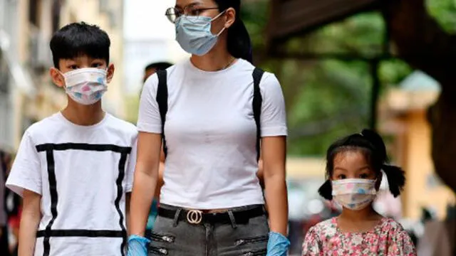 Madre e hijo caminan por la calle cubriendo su rostros para evitar el contagio. Foto: AFP.