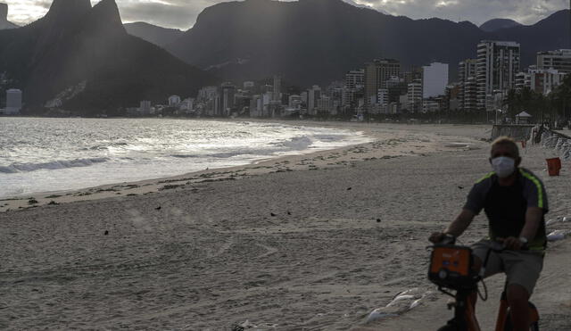 AME7007. RÍO DE JANEIRO (BRASIL), 22/03/2020.- Un hombre pasea de bicicleta con máscara en la playa de Arpoador, prácticamente vacía este domingo, en Río de Janeiro (Brasil). El número de muertes por COVID-19 en Brasil aumentó un 39 % en el último día, de 18 el sábado hasta 25 este domingo, mientras que el de casos confirmados subió un 37 %, desde 1.128 hasta 1.546 en el mismo período, según el último balance del Ministerio de Salud. En las últimas 24 horas se registraron 7 nuevas muertes y 418 nuevos casos, según el boletín. EFE/ Antonio Lacerda