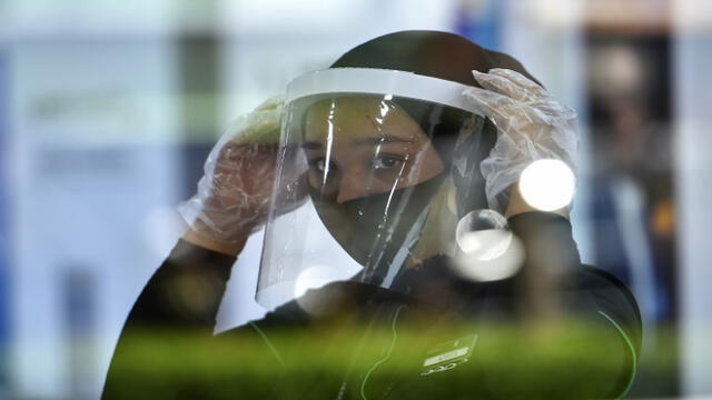An employee of a smartphone shop wears a face mask under a protective face shield to combat the spread of the COVID-19 coronavirus at a market in Banda Aceh on May 28, 2020. (Photo by CHAIDEER MAHYUDDIN / AFP)