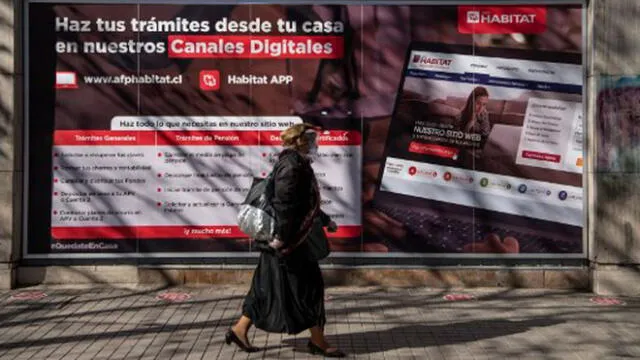 Una mujer pasa frente a una oficina de la Administración de Fondos de Pensiones (AFP) en Santiago. Foto: AFP.