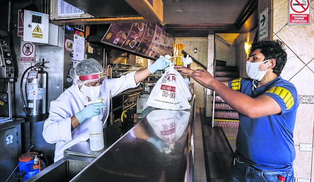 El personal que entrega las bolsas con los alimentos usa nuevos implementos como mascarillas, protectores faciales, guantes y desinfectante. (Foto: Oswald Charca)