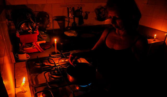 En la ciudad de San Cristóbal una mujer cocina, mientras se ilumina con velas, en un país con apagones constantes. Foto: EFE