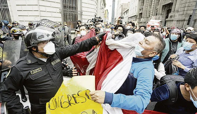 Afrenta. Un miembro de las fuerzas policiales es captado agrediendo a un manifestante que se negaba a que le quiten la bandera. Ocurrió en el jirón Carabaya el martes en la mañana. Pese a ello, el jefe de la PCM, Ántero Flores-Aráoz, y el ministro del Interior, Gastón Rodríguez, lo felicitaron. Foto: Antonio Melgarejo/La República