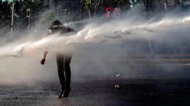 Un manifestante es rociado por un cañón de agua de la policía antidisturbios durante una protesta contra el gobierno del presidente chileno Sebastián Piñera en Santiago el 23 de octubre de 2020. Foto: AFP