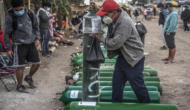 A man carries an empty oxygen tank as he arrives to queue to refill it in Villa El Salvador, on the southern outskirts of Lima, on April 11, 2021, amid the COVID-19 coronavirus pandemic. - Relatives of COVID-19 patients are desperate for oxygen to keep their loved ones alive during a fierce second wave of the pandemic in Peru, during the day of the first round of presidential and parliamentary elections. (Photo by ERNESTO BENAVIDES / AFP)