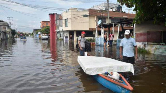 Dos hombre movilizan algunas de sus pertenencias en un bote en medio de una calle inundada por el paso de la tormenta Gamma y el paso del huracán Delta. Foto: EFE