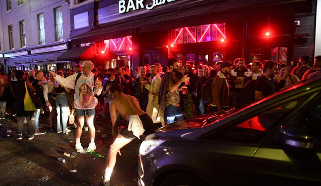 Auto intenta cruzar calle llena de juerguistas que beben en el área de Soho de Londres. Foto: AFP.