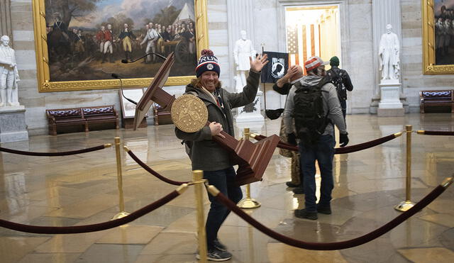 Hombre posó con el atril de la portavoz de la Cámara de Representantes en medio del asalto al Congreso de EE. UU. Foto: AFP