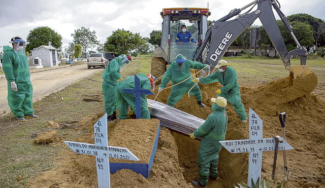 Dolor. Sepultureros entierran a víctima de COVID-19 en cementerio Senhora Aparecida, Manaos. Foto: AFP