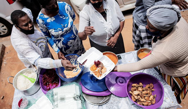 Un grupo de voluntarios en Thembisa (Sudáfrica) preparan raciones de alimentos, durante una distribución para comunidades desfavorecidas. Foto: AFP