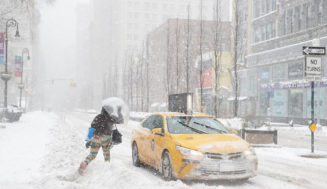 Una mujer corre hacia un taxi en Union Square, en Nueva York, EE. UU., durante la nevada de este 1 de Febrero. EFE/EPA/JASON SZENES