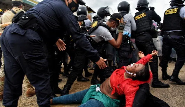 Una policía intenta levantar a una mujer en medio del caos que provocó, el martes 16, el abrupto ingreso de cientos de migrantes a Iñapari, en Madre de Dios. Los extranjeros fueron retornados a Brasil por la Policía. Foto: EFE.