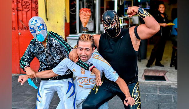 Los luchadores mexicanos Gran Felipe Jr. y su hermano Ciclonico pretenden castigar a un hombre que no usa máscara facial mientras hacen campaña para promover su uso. Foto: AFP