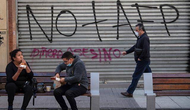 Hombre pasa por un grafiti contra la Administración de Fondos de Pensiones (AFP) en Santiago, el 15 de julio de 2020. Foto: AFP